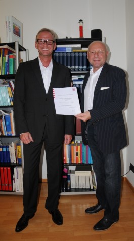 BU: Hohe akademische Auszeichnung: Prof. Dr. Lothar Jordan (rechts) übergibt die Urkunde des Ministeriums an Prof. Dr. Andreas Buschmeier. 