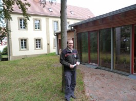 Norbert Diener im kleinen Park der historischen Anlage, der vom verglasten Mehrzweckraum im neuen Anbau aus zugängig ist.  Foto: Bickert